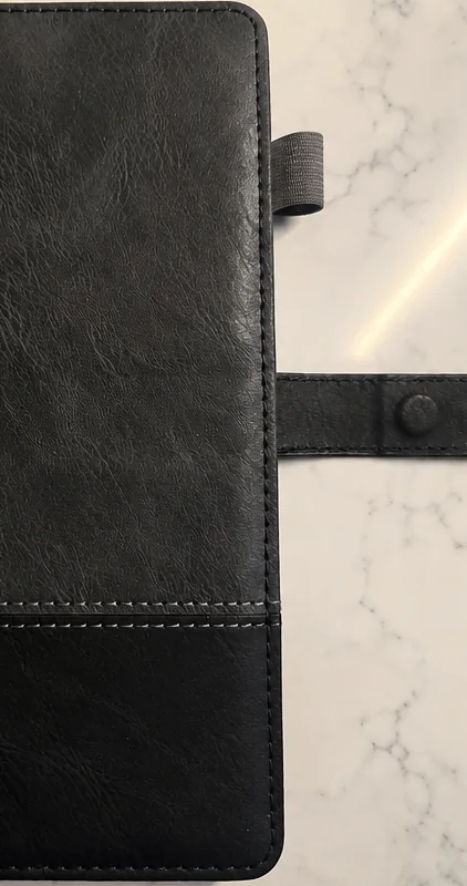 Black executive notebook with strap and pen loop on marble
